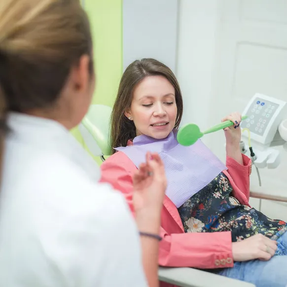 Pacijentkinja drži ogledalo i razgovara sa doktorkom
